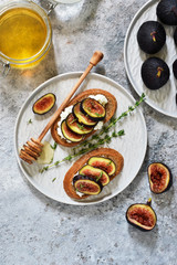 Toasts with ricotta, figs and honey for breakfast on a concrete background. Gourmet breakfast.