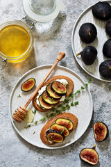 Toasts with ricotta, figs and honey for breakfast on a concrete background. Gourmet breakfast.