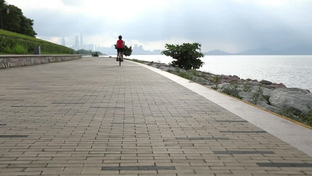 Woman Riding Bike on Seaside Road 