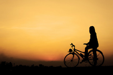 Fototapeta na wymiar Silhouette woman with bicycle, walking, sunset background