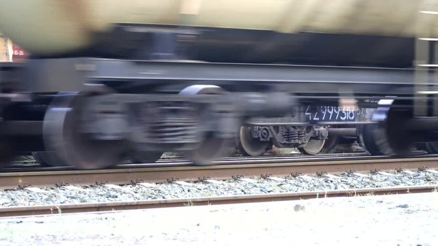 Petrol train passes by a camera. Wheels of the train moving along the rails closeup. 4K