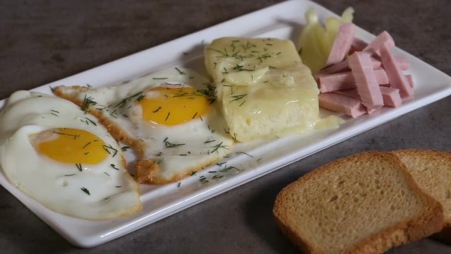 Spreading chopped dill over fried eggs with melted Romanian cheese called cas and some parizer