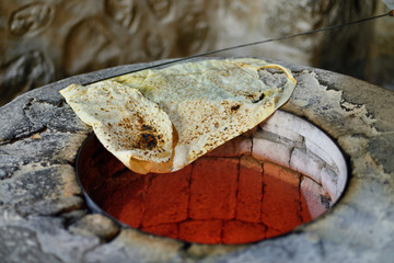 Armenia, Home made lavash bread being baked on a traditional Armenian floor oven. - obrazy, fototapety, plakaty