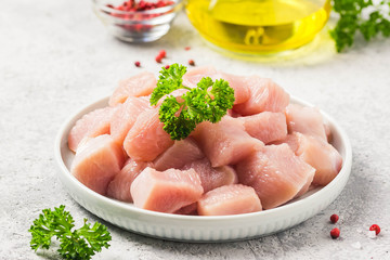 Raw meat cubes in a bowl with parsley, seasonings and olive oil. Selective focus, space for text.