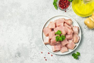 Raw meat cubes in a bowl with parsley, seasonings and olive oil. Top view, space for text.
