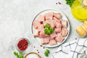 Raw meat cubes in a bowl with parsley, seasonings and olive oil. Top view, space for text.