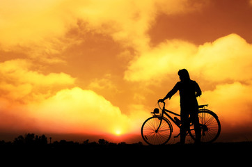Obraz premium Silhouette woman with bicycle, walking, sunset background
