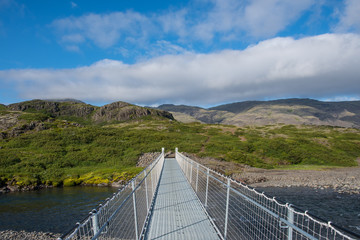 Walking bridge crossing river Kolgrafardalsa near nature resort of Haukafell in Iceland