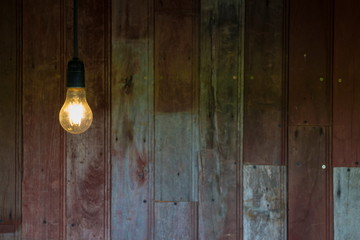 Light from vintage light bulb with old wood wall background, image with copy space.