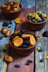 Mix of different varieties of dried fruits on wooden background - dates, apricots, prunes, raisins. Organic healthy food. Excellent snack or dessert