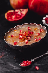 Turkish Dessert Ashura With Pomegranate, Noah's Pudding on Dark Wooden Background