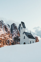 Sonnenuntergang im Winter an der verschneiten Kapelle am Grödner Joch in Südtirol