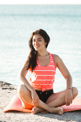 Fototapeta na wymiar Young beautiful woman doing yoga exercises on the beach