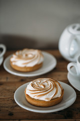Tartlet with lemon cream and meringue on old rustic wooden background