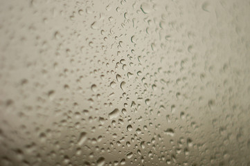 raindrops on window glass on background of cloudy sky