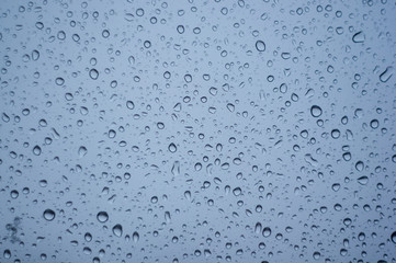 raindrops on window glass on background of cloudy sky