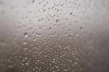raindrops on window glass on background of cloudy sky