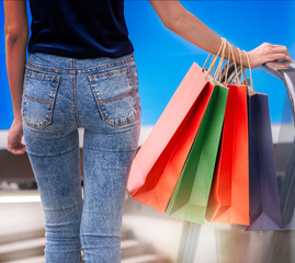 A woman holds a colorful bag from the mall.