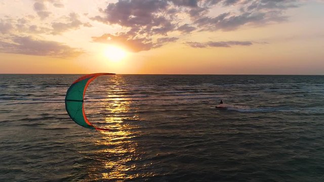 Sporty background, male kiter slides on the waves at sunset