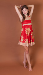 Naturally thin healthy brunette girl in the studio with a brown background with arms over head on toes