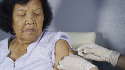 Doctor giving vaccine injection into senior woman