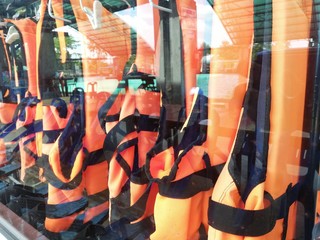 An orange life jacket hanging in a glass cabinet.