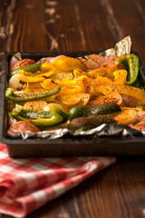 baking sheet, in the middle are vegetables, peppers, onions, potatoes and pieces of white meat sprinkled with spices and prepared for baking