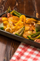 baking sheet, in the middle are vegetables, peppers, onions, potatoes and pieces of turkey meat sprinkled with spices and prepared for baking