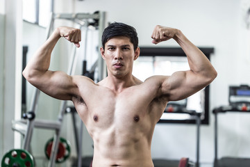 Fototapeta na wymiar Handsome Attractive Asian men doing bodybuilder Front Double Biceps pose in gym feeling so strong and powerful after workout,Bodybuilder Concept