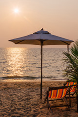 Beach chairs with umbrella on the sunset
