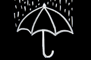 Drawing an umbrella with rain with chalk on a blackboard