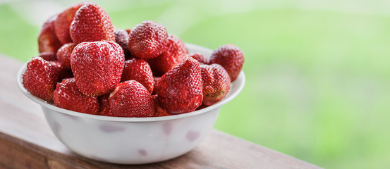 Fresh juicy large strawberry in a bowl close-up outdoors at the cottage, panoramic banner