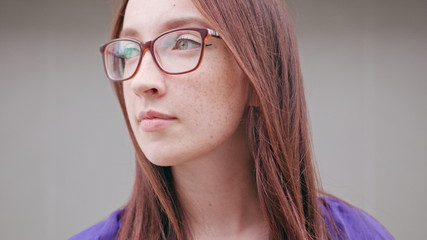 Fototapeta na wymiar A happy smiling brunette woman wearing glasses against a grey background. Close-up shot. Soft focus