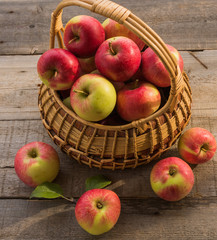 The basket with ripe apples  on old wooden table background.