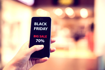 People, sale, consumerism, advertisement concept - close up of woman's hand holding shopping bags and smartphone with black friday inscription