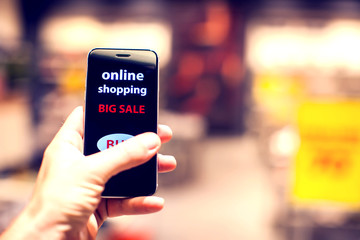 Fototapeta na wymiar People, sale, consumerism, advertisement and black friday concept - close up of man's hand holding shopping bags and smartphone with shopping online inscription