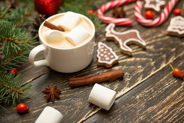Winter warming sweet drink hot latte with marshmallows and cocoa in a mug with a Christmas holiday cinnamon on a wooden background, selective focus