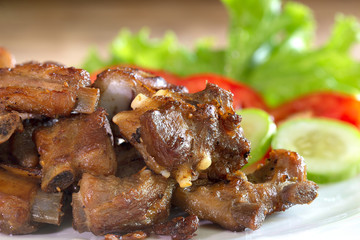 Fried deep pork ribs in white dish with vegetable thai food
