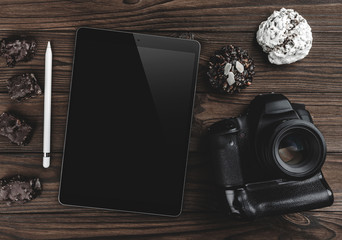 Top view of travel concept with digital camera, touch screen device - tablet with pen and biscuits on wooden background