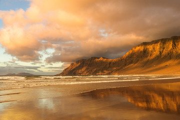 Golden Mounts toasted by the rays of the setting sun reflecting in the wet sand of the beach