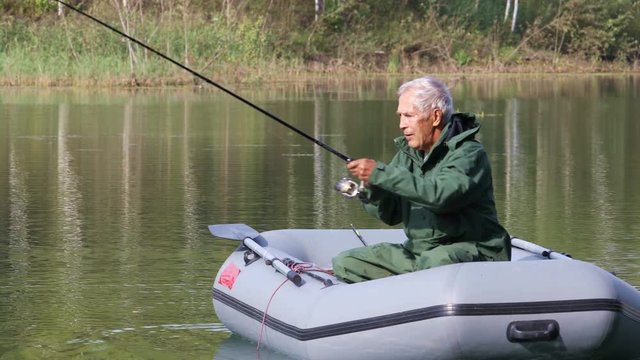 Retired fisherman catches fish from an inflatable boat on the lake, just caught carp
