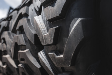 Big  set of black huge big truck, tractor or bulldozer loader wheel close-up on stand, shop selling tyres for farming and big vehicles Construction machinery. Lot of pattern tread of Off-road tires. 