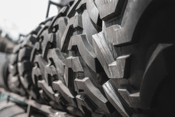 Big  set of black huge big truck, tractor or bulldozer loader wheel close-up on stand, shop selling tyres for farming and big vehicles Construction machinery. Lot of pattern tread of Off-road tires. 