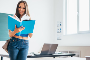 Portrait of female student holding book and reading