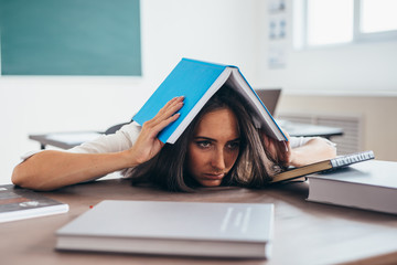 Tired young woman sleeping on desk with books
