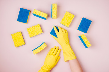 Female hands cleaning with sponge on pink background. Cleaning or housekeeping concept background. Copy space. Flat lay, Top view.