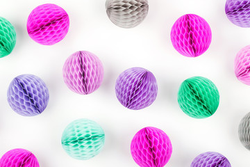 Honeycomb balls decorations pattern. Pink, lilac and turquoise paper pom pom on a white background. Flat lay.