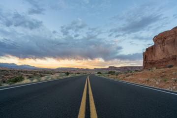 Fototapeta na wymiar Sunrise over a diminishing road in Arches National Park, the American southwest