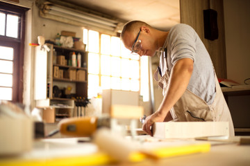 Carpenter working on woodworking machines in carpentry shop
