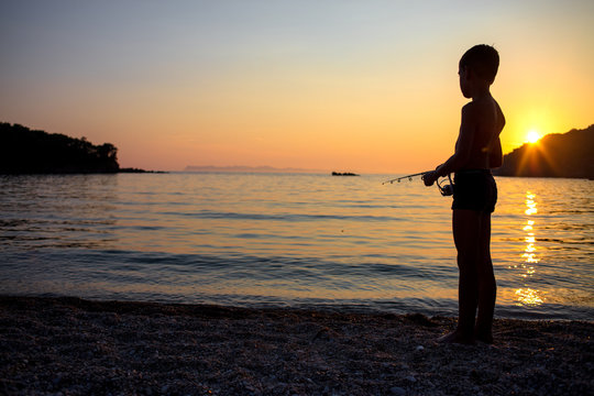 young boy fishing on the seashore
